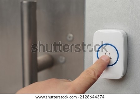 Hand pressing button on outdoor doorbell with an intercom 