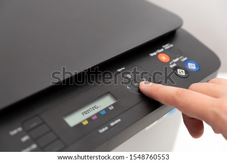 Hand pressing button on panel of printer. Multifunction device, printer, copier.