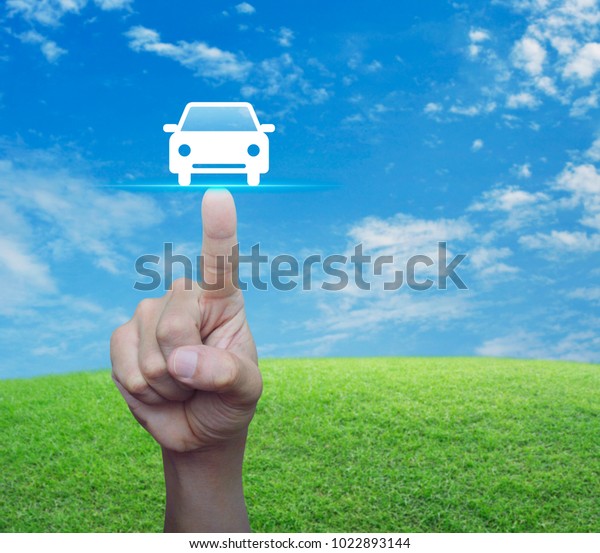 Hand\
pressing car flat icon over green grass field with blue sky,\
Business transportation taxi car service\
concept