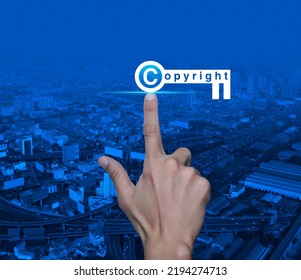 Hand Pressing Copyright Key Icon Over Modern City Tower, Street, Expressway And Skyscraper, Copyright And Patents Concept