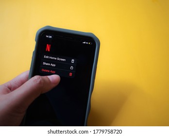 The hand is pressing to delete the Netflix app on the iPhone. unsubscribe Netflix. 
