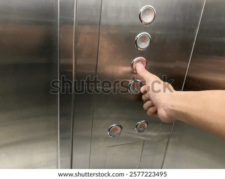 Hand Pressing the Elevator Panel Button in a Modern Lift Interior