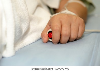 Hand pressing emergency nurse call button on bed.