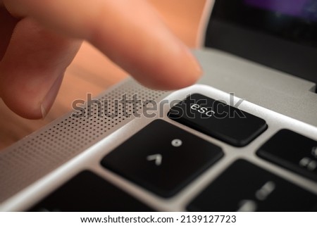 Hand pressing escape key on modern laptop keyboard. Esc sign and symbol closeup