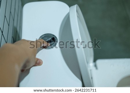 Hand pressing the flush button