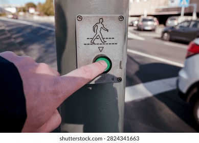 Hand pressing green button on a pedestrian crossing signal for urban road safety