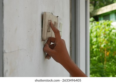 hand pressing the light switch button on the outside wall. turning the light switch on and off