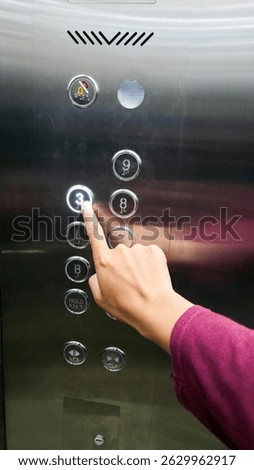 A hand pressing the third-floor button on a metal elevator panel. Ideal for daily activity visuals, vertical transport themes, or modern building facilities.

