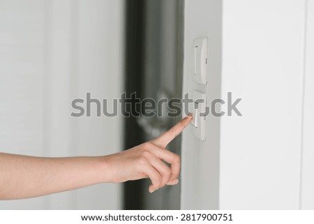Hand pressing wall switch in modern interior