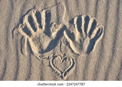 Hand print with heart in sand on beach. Corrugated sand. Still life on the seashore. Vacation memories from the coast - Shutterstock ID 2247247787