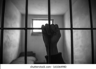 hand of a prisoner grabbed the bars of the prison