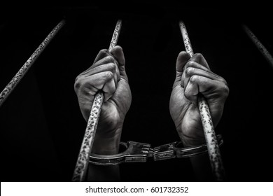 Hand of the prisoner on a steel lattice close up dark tone style