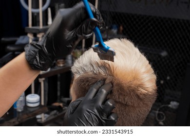 The hand of a professional hairdresser in a glove paints a guy's hair with a brush with white paint in a barbershop. - Powered by Shutterstock