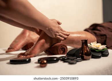 Hand of Professional masseuse service oil massage on foot preparing to hot stone on feet of customer in wellness spa centre. Hot stone foot massage concept, - Powered by Shutterstock