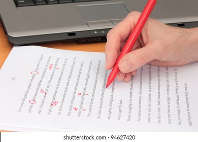 Hand Proofreading a Manuscript beside Laptop