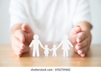 Handschützende Familie auf Holztisch. Konzept der Krankenversicherung und Lebensversicherung