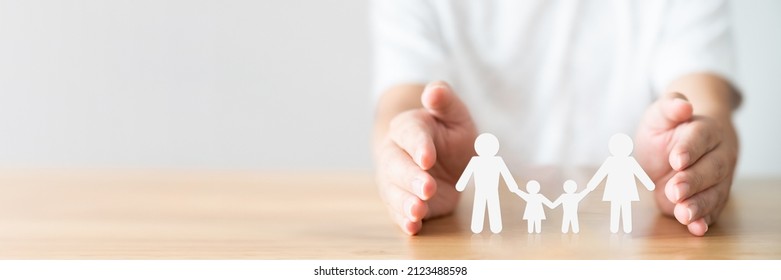 Hand Protecting Family On Wood Table. Healthcare And Life Insurance Concept