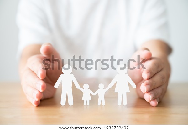 Hand protecting family on wood table. Healthcare\
and life insurance concept