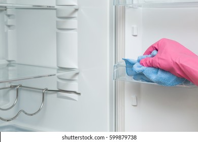 Hand In Protective Glove With Rag Cleaning Inside Of Fridge In The Kitchen. Early Spring Cleaning Or Regular Clean Up.