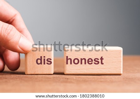 Hand pull out the wood block to split the text DISHONEST to be HONEST, dishonesty and honesty concept
