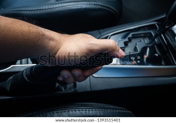 Hand pulling the hand\
brake in car 