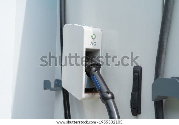 Hand pulling in cable from EV car charger or\
electric vehicle station. Cable connected at gas station, power\
supply battery charging an alternative eco environment future\
technology energy\
innovation