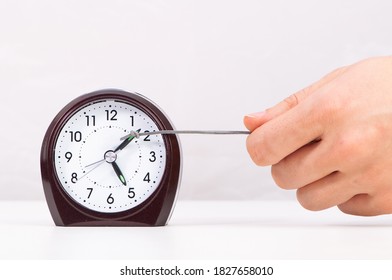 Hand pulling clock hand forward in time management concept - Shutterstock ID 1827658010