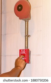 Hand pulling down the manual fire alarm station in case of fire emergency