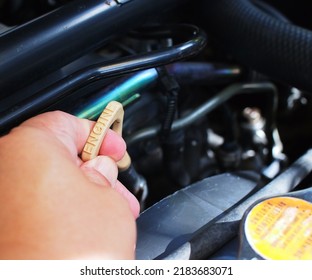 Hand Pulling Up The Oil Level Gauge Of The Car To Check.