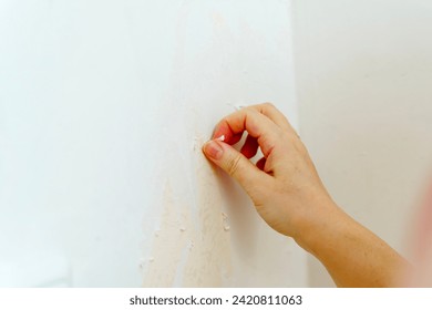 Hand pulling old wallpaper off the wall