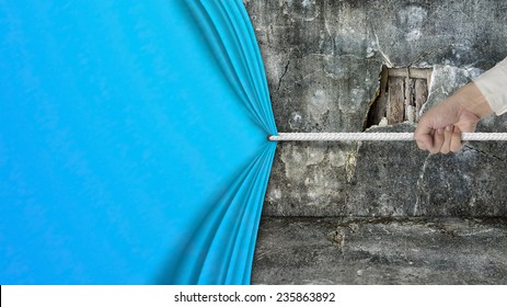 hand pulling open blank blue curtain covered old broken wall ruins background