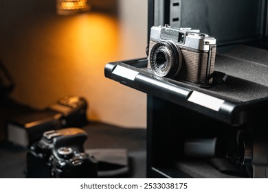 A hand pulling out a camera storage drawer containing a vintage camera and a modern SLR camera.