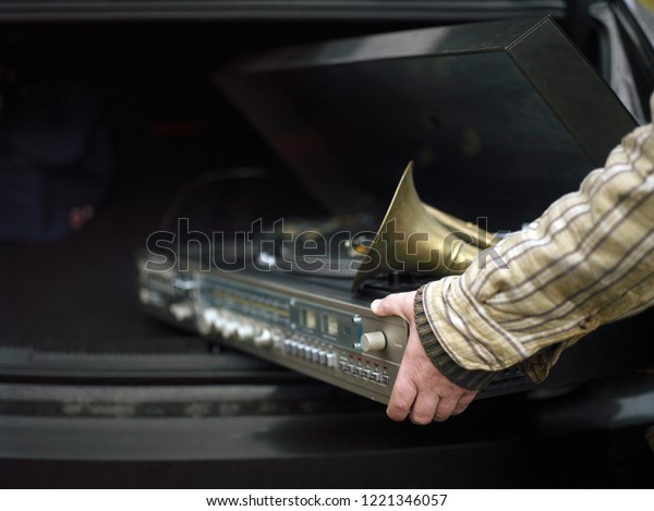A hand pulling out a car trunk a retro\
stereo music center and horn, concept of a\
party