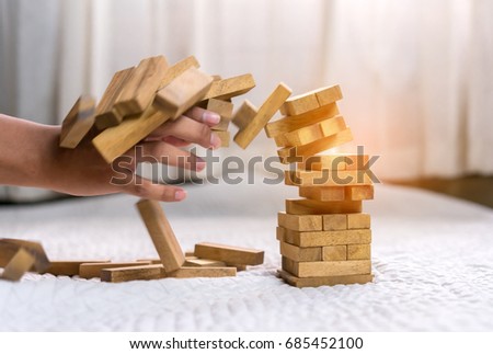 Hand of pulling out wood block fail on building tower at home and drape change, choice business risking dangerous project plan failure construction concept.