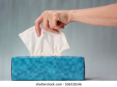 Hand Pulling White Tissue From Blue Box