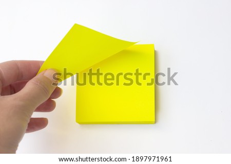 Hand pulls off yellow leaf post it. Blank yellow sticky note