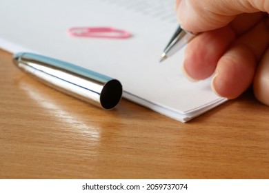 hand pulls a pen out of the cap and signs the document, closeup