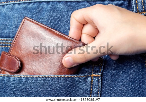 A
hand pulls a wallet out of the back pocket of his jeans.The concept
of pickpocketing or theft in the family from
parents.