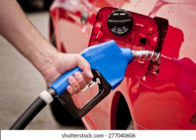 Hand Pumping Gas Into Red Car