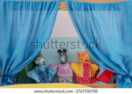 Hand puppets performing on a puppet theater stage with blue curtains, engaging children's imagination and storytelling