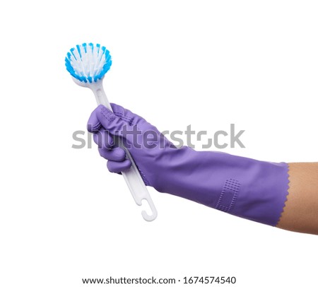 hand in purple rubber glove holds plastic brush for cleaning the house, part of the body is isolated on a white background
