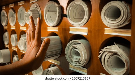 A hand push an old paper map rolled document file archive blueprint storage hardcopy conventional