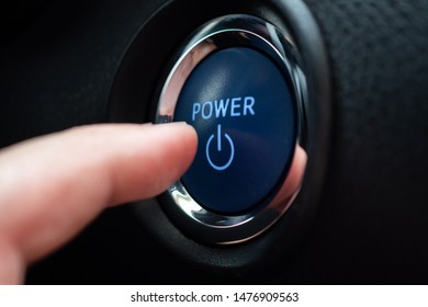 Hand push on car engine power start button close up