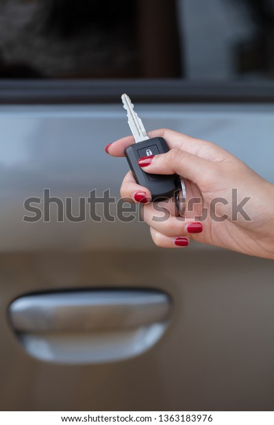 hand push an unlock botton on car key with car\
on background