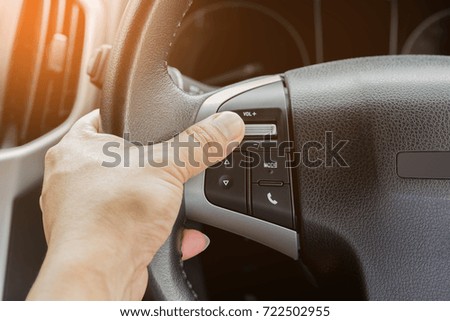 hand pushes control buttons on the steering wheel buttons on modern car and speed limitation