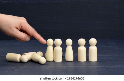 hand pushes the wooden figures of men, they fall in different directions. The concept of psychological pressure on a person, burnout. Dominance, repression and elimination of competitors - Shutterstock ID 1984194605