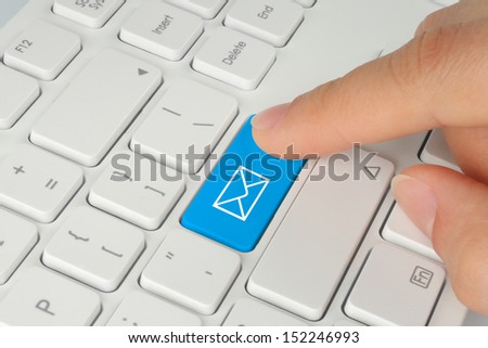 Hand pushing blue mail button on white keyboard background 