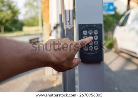 Hand pushing a button on a security keypad, unlocking access to a door or gate, ensuring safety and control for private properties