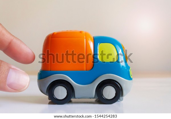 hand pushing a colorful toy\
truck 