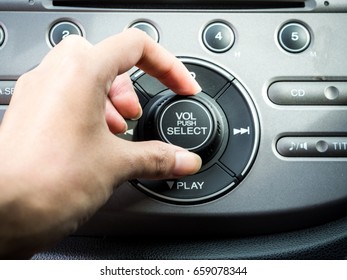 Hand Pushing the power button to turn on the car stereo system - Shutterstock ID 659078344